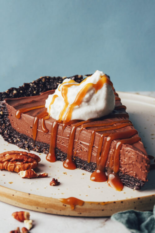 Slice of no-bake chocolate mousse pie drizzled with coconut whipped cream and caramel sauce
